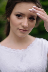 Naklejka premium Close up portrait of young tender bride woman with nude make up in white wedding dress outdors in the park. Wedding concept