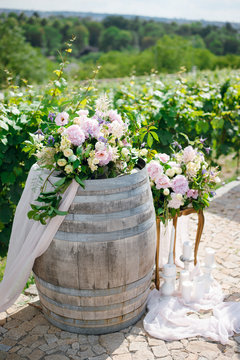 Elegant Floral Arrangement Wedding Ceremony Decor With Pink, White And Green Flowers On Wooden Wine Barrel Outdoors.