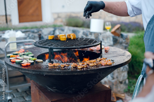 Man Salt Grilled Shrimps Corn And Vegetables On The Big Round Man Salt Grilled Shrimps Corn And Vegetables On The Big Round Flaming Bbq Grill Outdoors