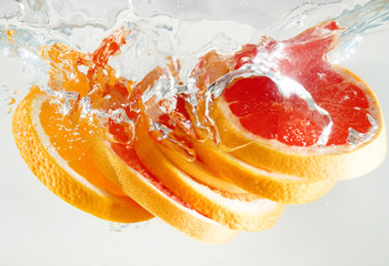 Grapefruit and orange falling to the water. Suitable for advertisement.