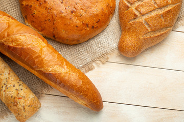 Fresh bread on a wooden table with flour and wheat,empty space. Concept baking, bakery