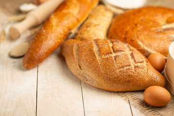 Fresh bread on a wooden table with flour and wheat, eggs and empty space. Concept baking, bakery