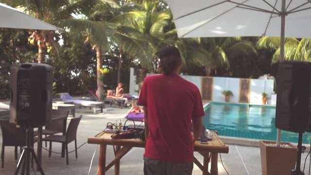 DJ from the back playing opposite people relaxing by the pool
