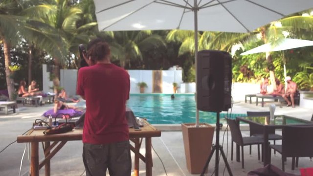 DJ playing opposite people relaxing by the pool