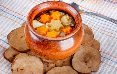 Traditional rustic home  gulyas, with raw vegetables and spices in clay pots on  wooden table.