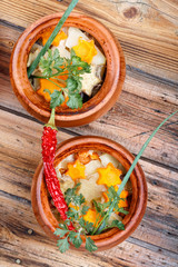 Traditional rustic home  gulyas, with raw vegetables and spices in clay pots on  wooden table.
