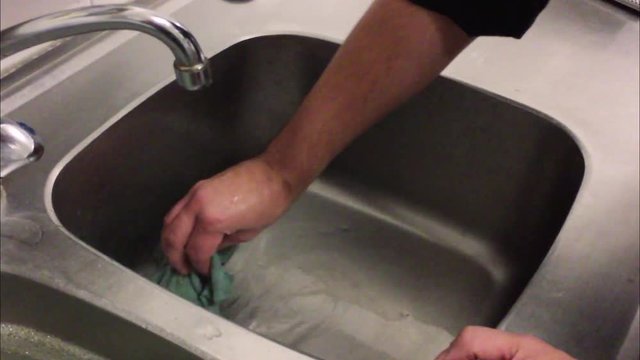 Using a clean cloth for wiping the sink