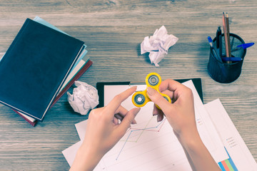 Concept of using fidget spinner at work while having a break. Hands holding fidget spinner over...