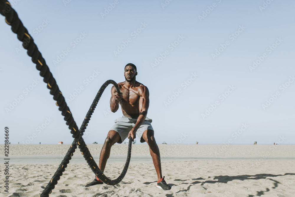 Wall mural fit man working out with battle ropes