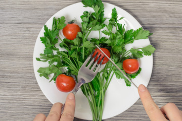 Close up top view photo of woman's hands cut cherry tomato on plate with parsley in form of green tree