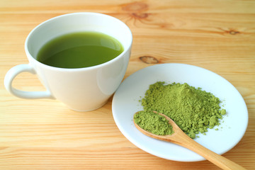 Matcha Tea Powder with a Wooden Spoon and a Cup of Hot Matcha Green Tea on the Wooden Table