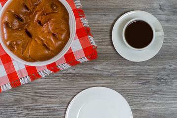 Overhead view photo of homemade cherry pie, cup of hot fresh tea and empty plate on wooden table