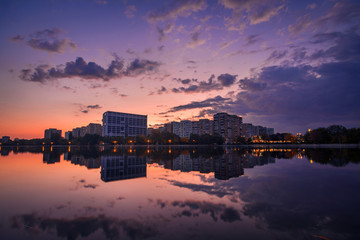Fototapeta na wymiar Beautiful sunrise cityscape scene on a lake with mirror reflection