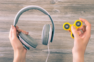 Concept of combining listening to music and using popular fidget spinner. Close up photo of hands...