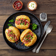 Baked stuffed potatoes with bacon, green onion and cheese, top view.