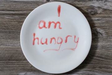 A plate with inscription I am hungry on it written with red berry sauce