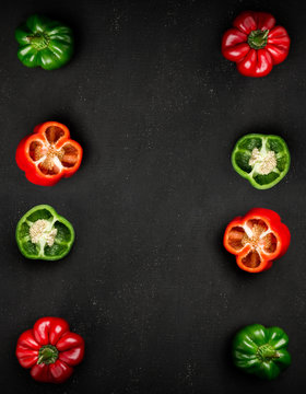 Flat lay composition with red and green paprika peppers (whole and half) on black background. Top view