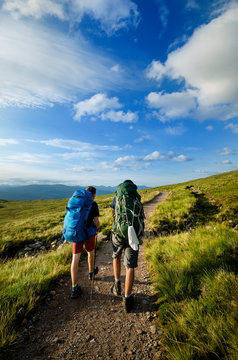 Tourist Friends On A Top Of Mountains In A Scottish Highlands. Scotland Nature. Tourist People Enjoy A Moment In A Nature.
 Tourists Favourites Place In Scotland - Isle Of Skye.