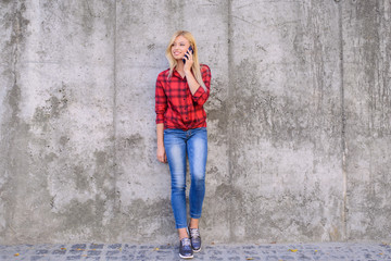 Young pretty woman talking on mobile phone while having a walk in a city