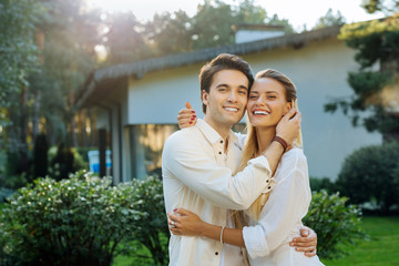 Loving relationships. Joyful nice happy couple smiling to you while hugging each other