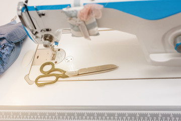 Designer accessories: sewing machine and scissors on wooden table
