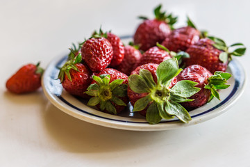 Close up of a bowl of juicy and ripe fruit, strawberries and grapes. vintage background, shallow depth in focus. Concept rustic nostalgia.