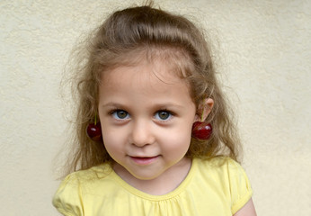 Naklejka premium Portrait of the little girl with sweet cherry berries as earrings on ears
