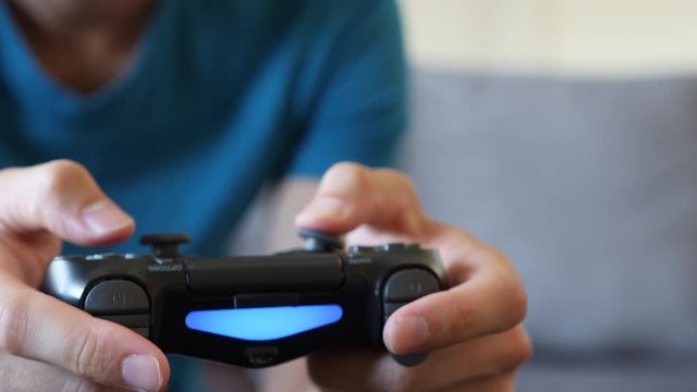Young Man Playing a Video Game on a Couch, Close Up of the Controller