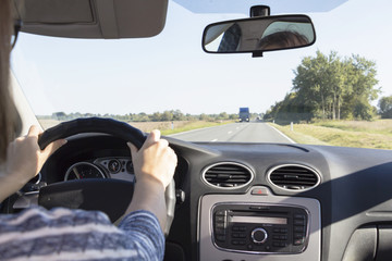 Close-up of the woman's hand holding the steering wheel. Girl driver rides behind the wheel of a car