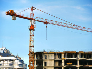 Construction site. Crane near building. Crane and building under construction.