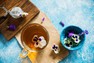 Obraz na płótnie Canvas Flower tea: pansies, edible flowers, on a light background