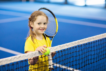 Child playing tennis on indoor court
