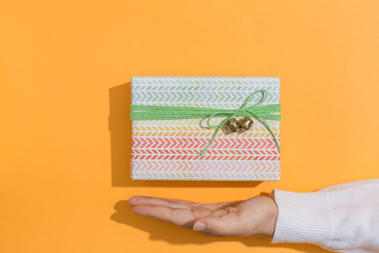 Woman holding a gift box on a orange background