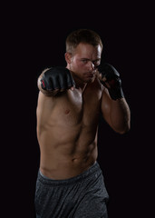 Fototapeta na wymiar Young well muscled Caucasian adult male wearing mma gloves throwing a right hand punch