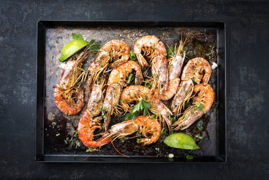 Traditional fried black tiger prawn with lemon as top view on a rustic old board