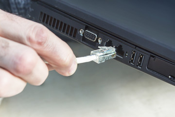 Dłoń mężczyzny wkłada wtyczkę ethernet RJ45 do internetu. Podłączanie internetu przez kabel...