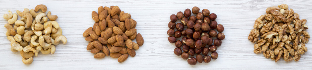 Assortment of nuts (cashew, hazelnuts, walnuts, almonds) on white wooden surface. Top view, overhead, from above.