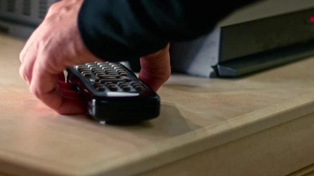 Male take remote TV control off the table near TV