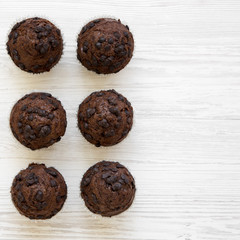 Chocolate muffins on white wooden surface, overhead view. Copy space.