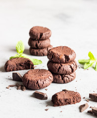Chocolate cookies with pieces of chocolate and mint on a grey concrete background. Selective focus.