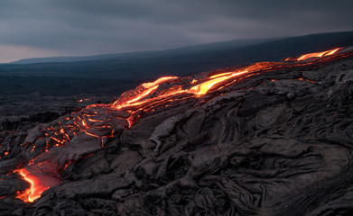 Closeup of glowing lava flow from Puu Oo in the evening on the Pali in Kalapana, Big Island, Hawaii.