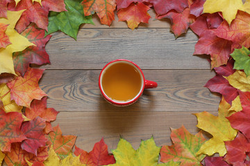 Cup of tea on a wooden table with autumn leaves the top view