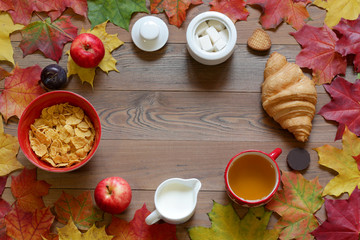 Breakfast on a wooden table with autumn leaves the top view