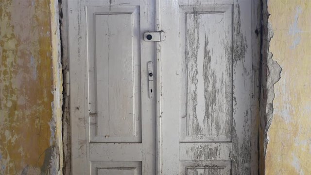 Stare porysowane i zniszczone białe drzwi bez klamki