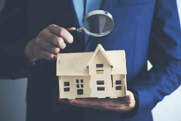 man hand holding house model and magnifier