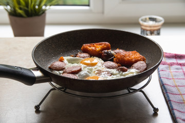 Barchelor breakfast - fried eggs with sausages on a teflon frying pan