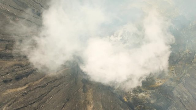 Flight over the active crater of the volcano, white smoke. Aerial view of volcano crater Mount Gunung Bromo is an active volcano,Tengger Semeru National Park. 4K video. Aerial footage.