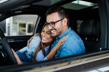 Beautiful young couple at car showroom choosing a new car to buy.