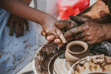 master of pottery teaches a little girl how to keep fingers