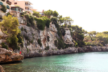 Fototapeta na wymiar Impressive sea cliffs and people jumping in the sea at Porto Cristo, Mallorca, Spain